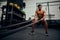 Young African American male exercising inside a gym. Topless male personal trainer using rope to strengthen his arms