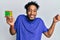 Young african american man with beard playing colorful puzzle cube intelligence game screaming proud, celebrating victory and