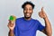 Young african american man with beard playing colorful puzzle cube intelligence game smiling happy and positive, thumb up doing