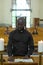 Young African American man in black shirt with clerical collar reading Gospel