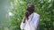 Young African American man in doctor uniform standing outdoors on sunny day praying in slow motion. Handsome