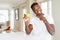 Young african american man eating fresh green apple very happy pointing with hand and finger