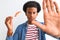 Young african american man eating nigiri using chopsticks over isolated white background with open hand doing stop sign with