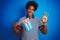 Young african american man holding Cuba Cuban flag standing over  blue background doing ok sign with fingers, excellent