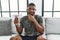 Young african american man holding diet banner sitting on the sofa at home serious face thinking about question with hand on chin,