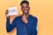 Young african american man holding healthy hashtag paper smiling happy pointing with hand and finger