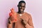 Young african american man holding heat water bag smiling happy pointing with hand and finger