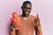 Young african american man holding heat water bag smiling with an idea or question pointing finger with happy face, number one