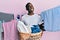 Young african american man holding laundry basket smiling looking to the side and staring away thinking