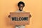 Young african american man holding welcome doormat smiling with a happy and cool smile on face