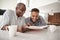 Young African American  man looking at a photo album at home with his grandfather, close up