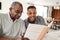 Young African American  man looking at a photo album at home with his grandfather, close up