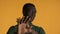 Young African American man looking serious showing stop gesture on camera over yellow background. Don`t want to watch