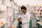 Young African American man pharmacist standing in interior of pharmacy. Man specialist of pharmacy making notes on