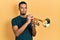 Young african american man playing trumpet relaxed with serious expression on face