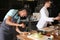 Young African-American man preparing tasty meat with salad in restaurant kitchen during cooking classes