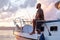 Young african american man standing with fishing rod on a sailboat fishing in open sea on sunset
