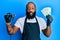 Young african american man tattoo artist wearing professional uniform and gloves holding tattooer machine and russian ruble