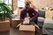 Young african american man unpacking books cardboard box at new home