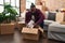 Young african american man unpacking books cardboard box at new home