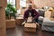 Young african american man unpacking books cardboard box at new home