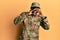 Young african american man wearing army uniform shouting angry out loud with hands over mouth