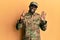 Young african american man wearing army uniform showing and pointing up with fingers number eight while smiling confident and