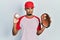 Young african american man wearing baseball uniform holding glove and ball relaxed with serious expression on face