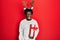 Young african american man wearing deer christmas hat holding gift winking looking at the camera with sexy expression, cheerful