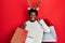 Young african american man wearing deer christmas hat holding shopping bags smiling and laughing hard out loud because funny crazy