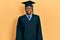 Young african american man wearing graduation cap and ceremony robe looking at the camera blowing a kiss on air being lovely and