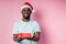 Young african american man wearing Santa hat holding gift