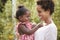 Young African American mother holds baby daughter in garden