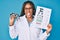 Young african american optician woman with braids holding optometry glasses and medical exam sticking tongue out happy with funny