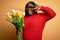 Young african american plus size woman with braids holding bouquet of yellow tulips flower Doing peace symbol with fingers over