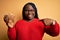 Young african american plus size woman with braids holding bowl with healthy peanuts with surprise face pointing finger to himself