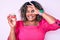 Young african american plus size woman holding cupcake smiling happy doing ok sign with hand on eye looking through fingers