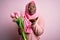 Young african american plus size woman wearing muslim hijab holding bouquet of pink tulips looking at the camera blowing a kiss