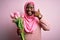 Young african american plus size woman wearing muslim hijab holding bouquet of pink tulips Pointing with hand finger to face and