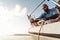 Young african american sailor tying ropes on sailboat in the sea on sunset