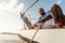 Young african american sailor tying ropes on sailboat in the sea on sunset