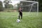 Young African American soccer player kicking the ball away from the goal during a soccer game on a large grass field