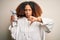 Young african american sportswoman with afro hair holding bottle of water with angry face, negative sign showing dislike with