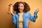 Young african american woman with afro hair holding jar with healthy macaroni pasta screaming proud and celebrating victory and