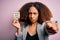 Young african american woman with afro hair holding paper with you are fired message pointing with finger to the camera and to