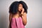 Young african american woman with afro hair wearing a body towel after beauty care shower looking stressed and nervous with hands