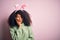 Young african american woman with afro hair wearing easter rabbit ears costume over pink background thinking looking tired and