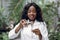 Young African American woman biologist in white coat pouring liquid from flask into test tube, while working in