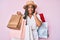 Young african american woman with braids holding shopping bags winking looking at the camera with sexy expression, cheerful and