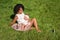 Young african american woman breastfeeding her baby sitting on grass in summer park. Infancy, motherhood, lactation, nutrition and